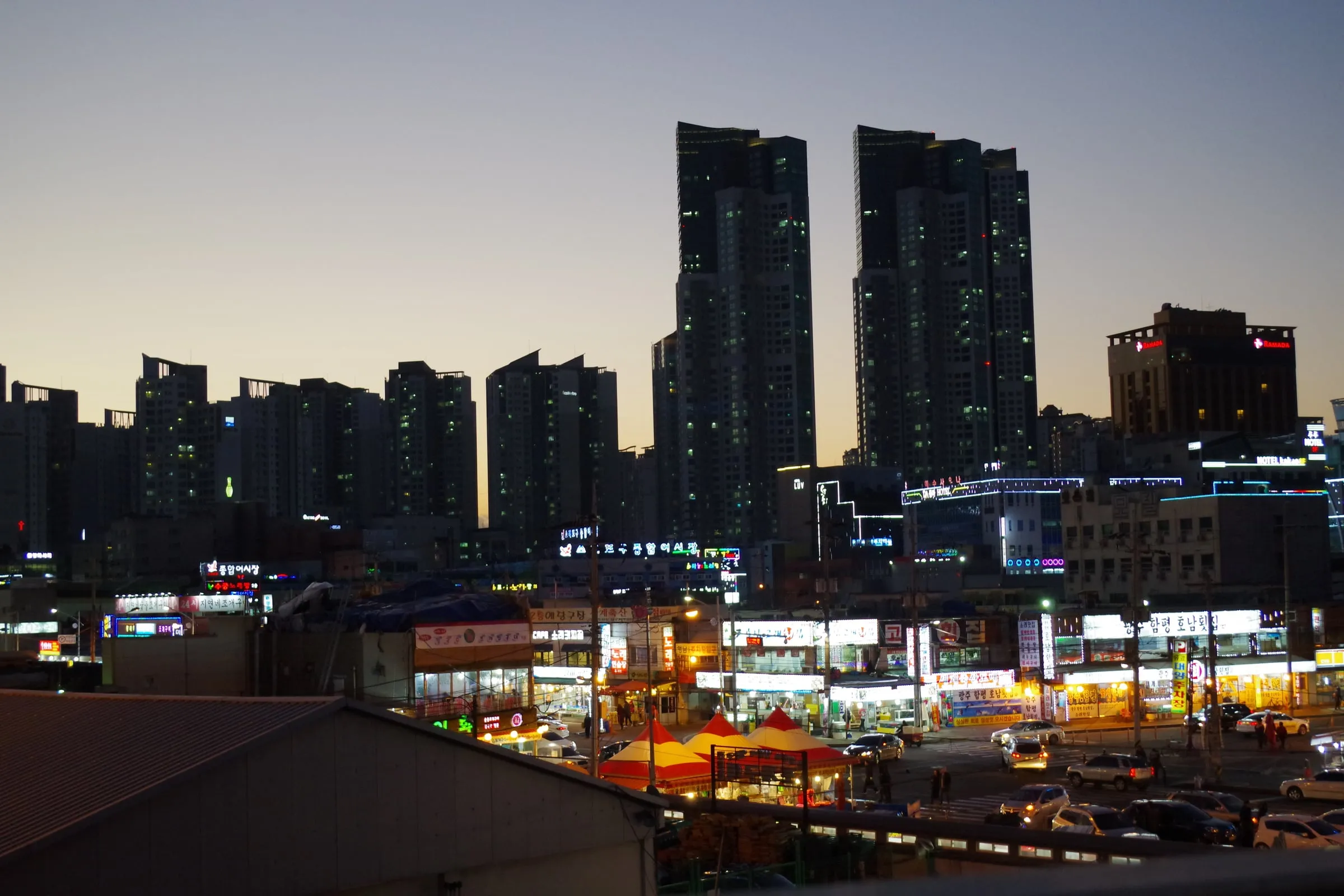 저녁 불이 켜진 포구 상가와 고층 아파트